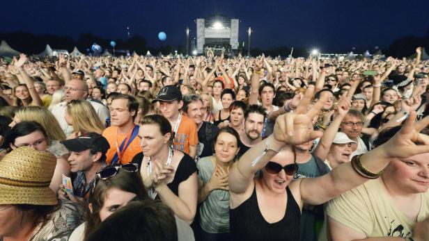 Eine große Menschenmenge jubelt bei einem Open-Air-Konzert vor einer Bühne.
