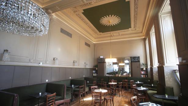 Ein elegantes Café mit Sitzgruppen und einem großen Kristalllüster.