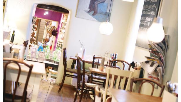 Einladendes Interieur eines kleinen Restaurants mit Holztischen und Stühlen.