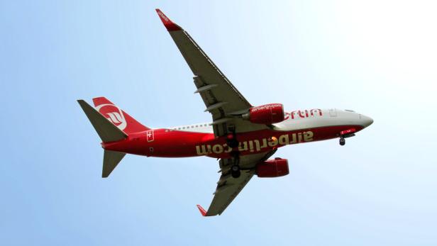 Ein rot-weißes Flugzeug der Air Berlin im Landeanflug vor blauem Himmel.