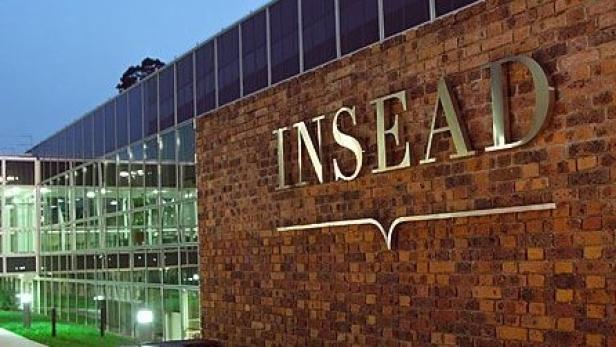 Das INSEAD-Logo an der Fassade eines Backsteingebäudes.