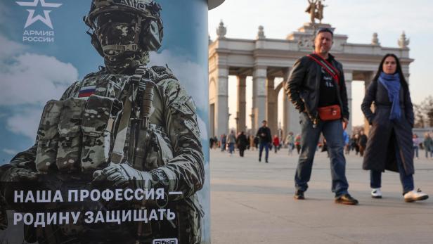 People walk past a desk promoting Russian army service in Moscow