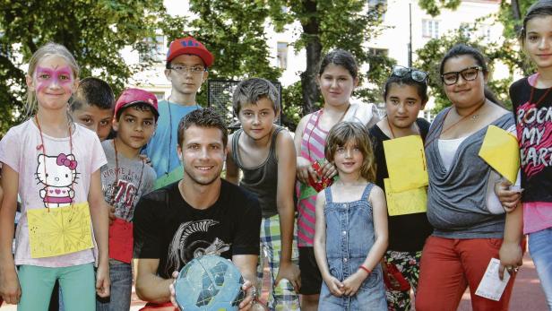 Eine Gruppe Kinder posiert mit einem Mann, der einen Globus-Ball hält.