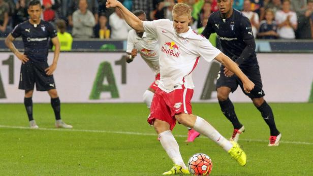Ein Fußballspieler in einem weißen Trikot mit rotem Aufdruck schießt einen Ball.