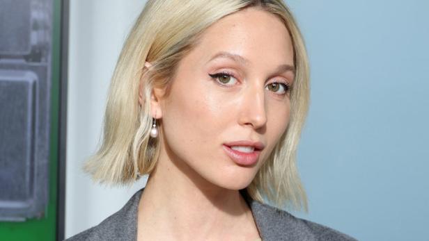 Eine Frau mit blonden Haaren und einem grauen Blazer blickt in die Kamera.