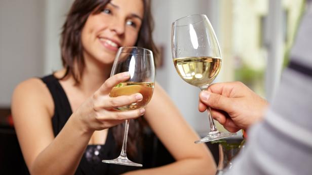 Frau stoßt mit Weinglas an.