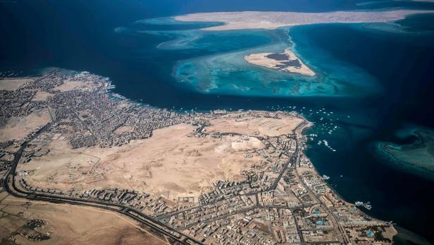 Luftaufnahme einer Küstenstadt mit vorgelagerten Inseln und türkisfarbenem Wasser.