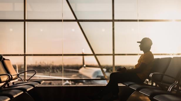 Ein Mann sitzt in einem Wartebereich am Flughafen.