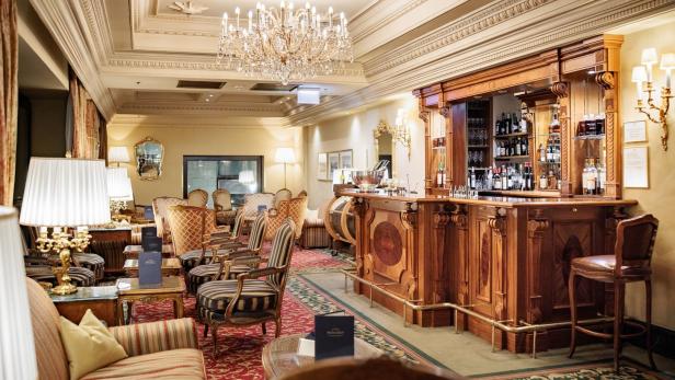 Eine elegante Hotelbar mit dunklem Holz und Kristalllüster.