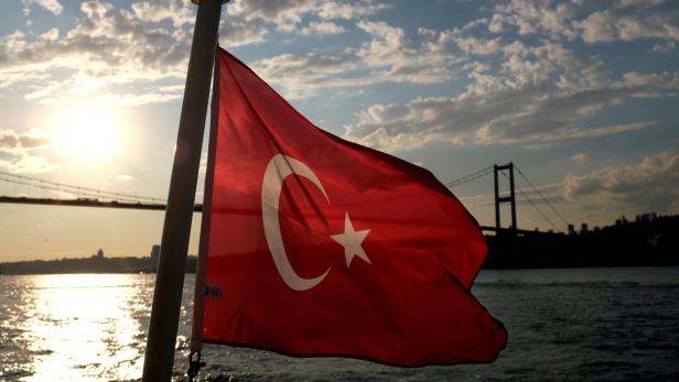 FILE PHOTO: A Turkish flag with the Bosphorus Bridge in the background flies on a passenger ferry in Istanbul