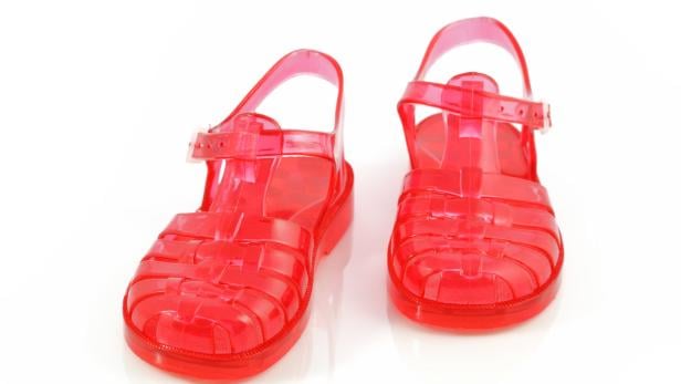 Ein Paar rote, durchsichtige Sandalen aus Kunststoff stehen auf einem weißen Hintergrund.
