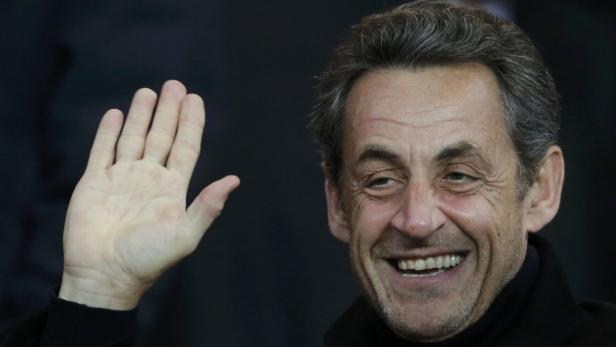 Nicolas Sarkozy lächelt und winkt in die Kamera.