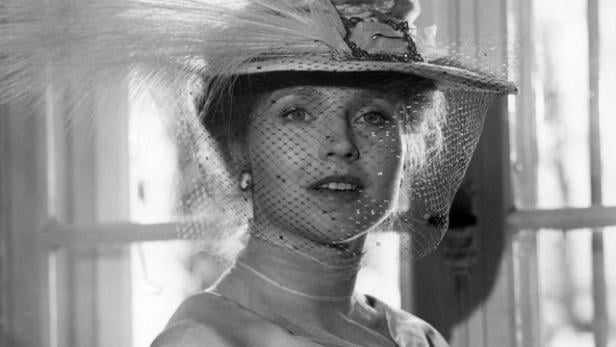 Eine Frau mit einem Hut mit Federn und einem Schleier vor dem Gesicht.