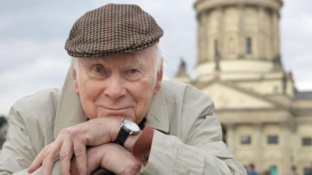Ein älterer Mann mit Schiebermütze lehnt an einem Gehstock vor dem Konzerthaus Berlin.