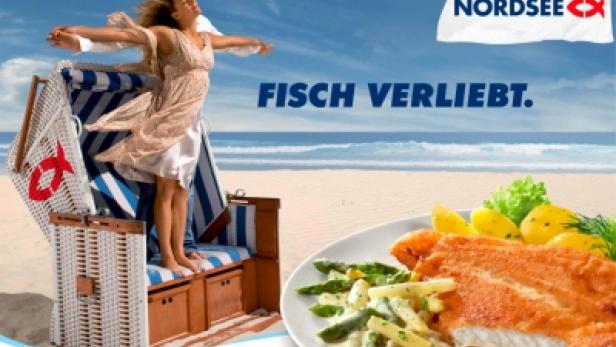 Eine Frau steht in einer Strandkorb-Szene am Meer, daneben ein Teller mit Schollenfilet und Spargelragout.