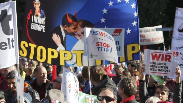 Demonstranten protestieren gegen TTIP mit Plakaten und Bannern.