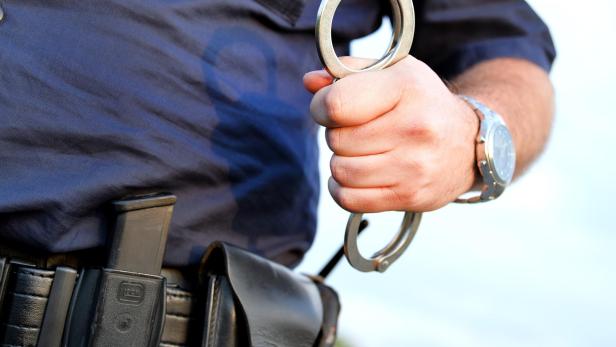 Polizei hält Handschellen in der Hand.