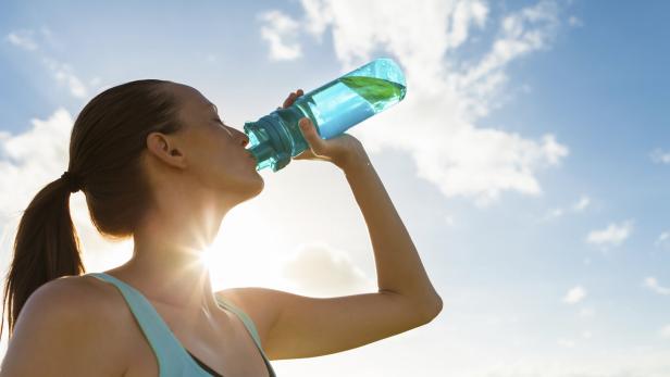 Sportliche Frau trinkt aus Flasche