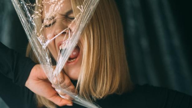 Eine Frau mit blonden Haaren kämpft mit einer Plastikfolie.