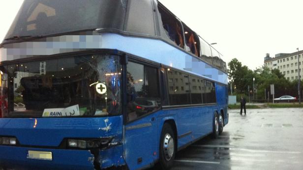 Ein blauer Doppeldeckerbus mit Unfallschäden an der Frontscheibe und der Karosserie steht auf einem Parkplatz.