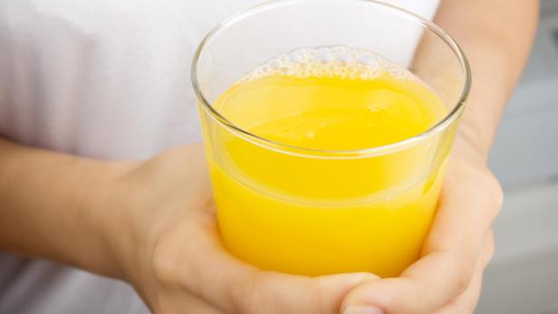 women's hands holding a glass of orange juice