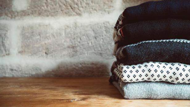Ein Stapel gestrickter Wollpullover auf einem Holztisch.