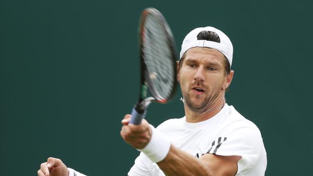 Ein Tennisspieler mit weißer Kappe schlägt einen Ball mit seinem Schläger.