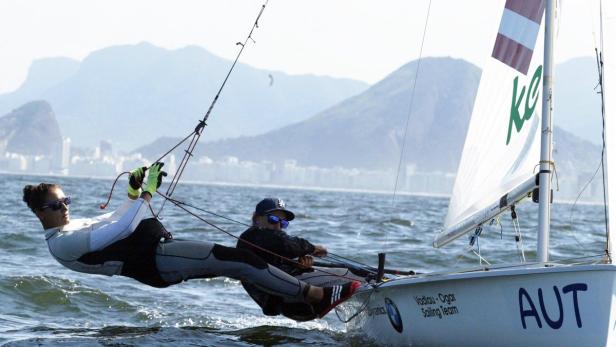 Zwei Seglerinnen des österreichischen Teams Vadlau-Ogar segeln auf dem Meer vor einer Bergkulisse.