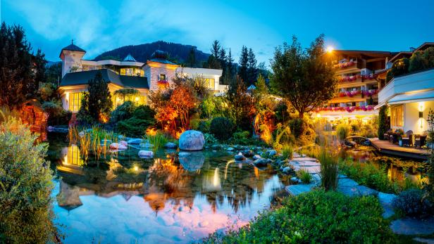 Ein Teich spiegelt die Lichter eines Hotels und der umliegenden Gärten wider.