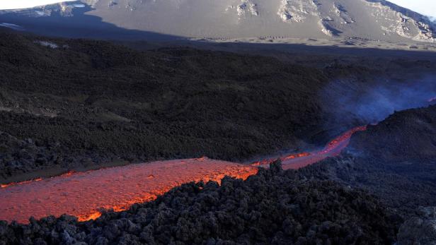 FILE PHOTO: Long streams of red-hot lava flow down the southeast crater of Mount Etna, Europe's tallest and most active volcano