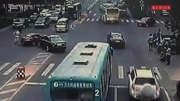 Eine belebte Straßenkreuzung mit mehreren Autos, Bussen und Fußgängern.