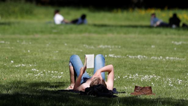 A visitor to Hyde Park reads in the sunshine in London