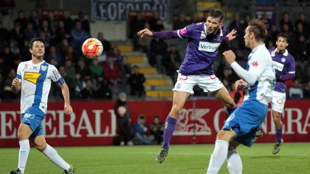 Ein Fußballspieler springt, um den Ball zu köpfen, während andere Spieler zusehen.