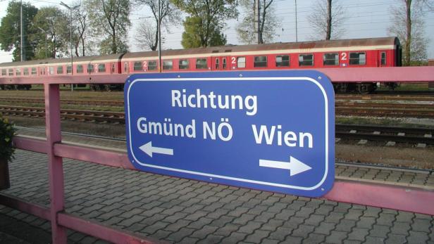 Ein blaues Schild auf einem Bahnsteig weist die Richtung nach Gmünd NÖ und Wien.