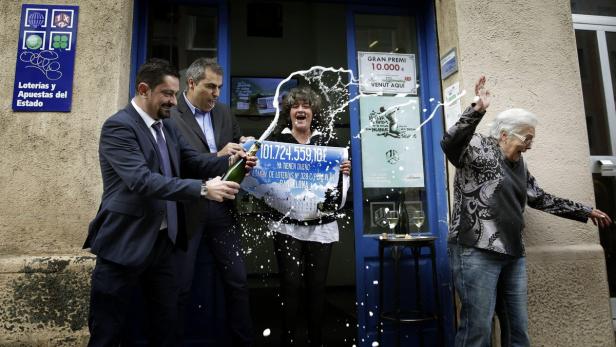 Menschen feiern einen Lottogewinn mit Champagner vor einem Lottogeschäft in Barcelona.