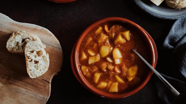 Erdäpfelgulasch in einer Schüssel mit Brot.