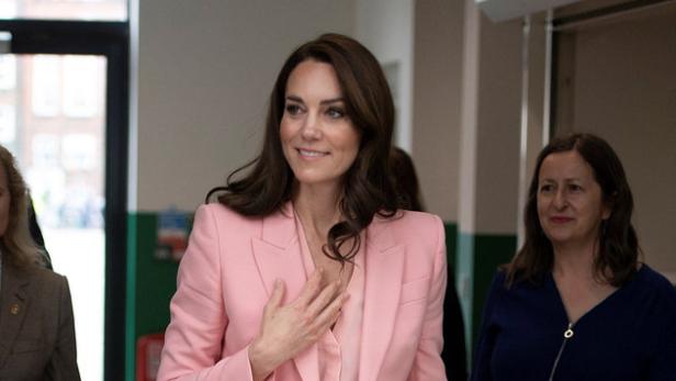 Kate Middleton trägt einen rosa Hosenanzug und weiße Schuhe.
