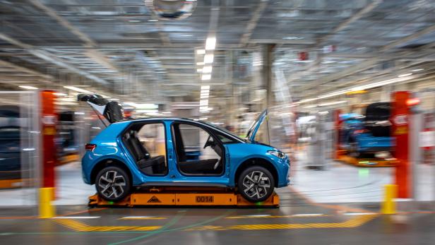 Ein blaues Auto ohne Türen und mit geöffneter Motorhaube auf einer Produktionslinie.