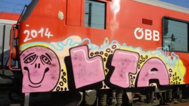 Ein roter ÖBB-Zug ist mit Graffiti besprüht.