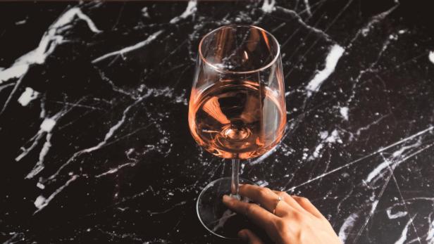 Ein Glas Roséwein steht auf einem schwarzen Marmortisch.
