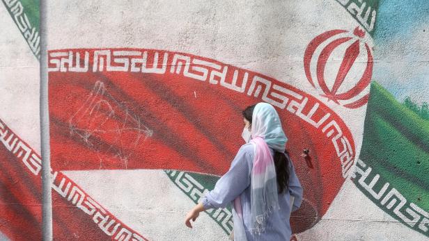 Frau mit Hidschab vor iranischer Flagge