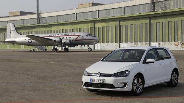 Ein weißer VW e-Golf steht vor einem Flugzeug vom Typ Douglas C-47 Skytrain.