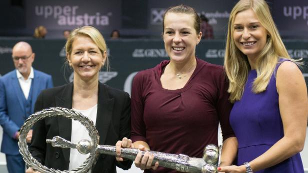 Drei Frauen posieren mit einer silbernen Trophäe in Form eines Schlüssels.
