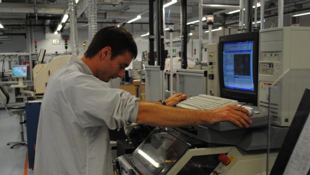 Ein Mann bedient eine Maschine mit Computer in einer Fabrikhalle.