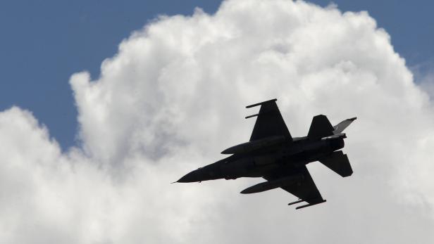 Ein Kampfjet fliegt vor einem Himmel mit weißen Wolken.