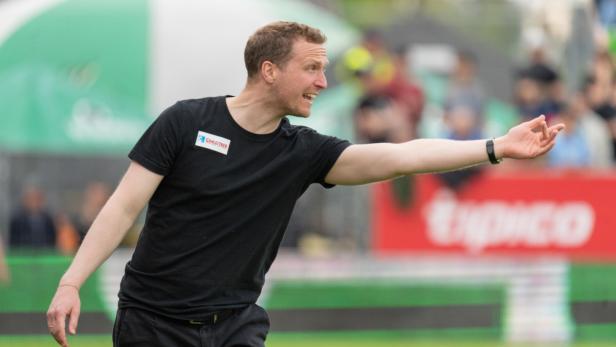 Ein Trainer gestikuliert während eines Fußballspiels.