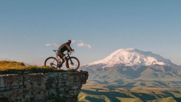 Mann mit Rad auf einem Berg.