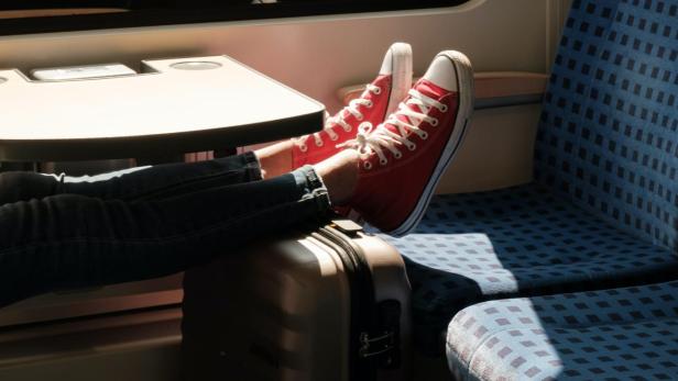 Füße mit Schuhen und ein Koffer in der Deutschen Bahn.