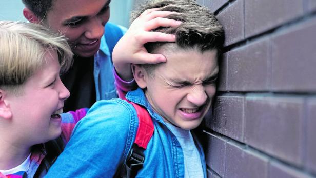 Cruel teenagers bullying, pushing classmate to wall, threatening physical harm