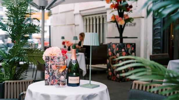 Eine Flasche Bollinger Rosé Champagner und ein Glas auf einem Tisch im Freien.